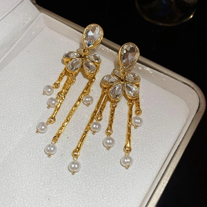 Détail de boucles d'oreilles de luxe avec pompons dorés et perles blanches en boîte