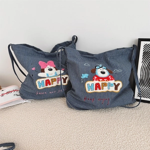 Detail of blue striped canvas tote bag with happy dog embroidery on plush white carpet
