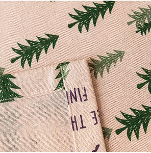 Detail of Christmas tree print on beige faux linen fabric with hem stitch finish