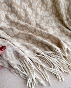 Close-up of leopard pattern knit scarf with beige fringe details and soft cashmere texture
