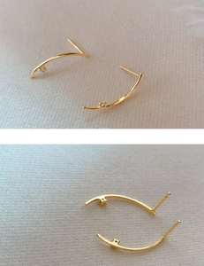 Close-up of minimalist gold curved stud earrings featuring a tiny clear zircon stone