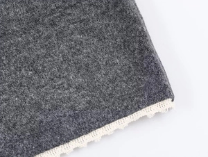 Detailed close-up of grey knitted fabric with delicate off-white lace trim detailing