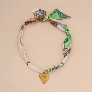 Resort style heart pendant necklace featuring green silk scarf woven chain and gold finish