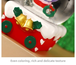 Close-up of a festive Christmas snow globe base with gold bells and white snow details