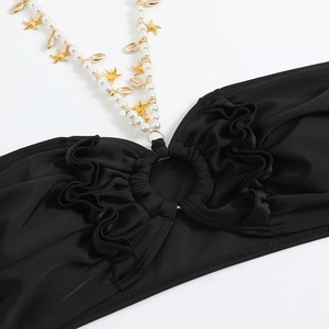 Dettaglio top bikini con stelle marine dorate, perle bianche e tessuto nero arricciato