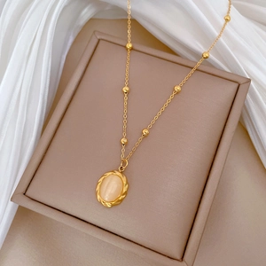 Detail of gold titanium necklace featuring opal pendant and beads on silk background
