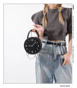 Detail of unique black vintage alarm clock shaped PU leather handbag with metal hands