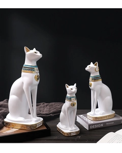 Dettaglio di tre statue di gatto egiziano in resina bianca con collari dorati e geroglifici