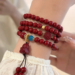 Detail of red cinnabar multi-layer bead bracelet featuring lucky rabbit charm and tassel