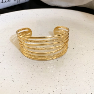 Detail of gold multilayer open cuff bracelet featuring smooth and hammered metal textures