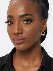 Macro detail of multi-layer gold plated hoop earrings worn on female model's ear