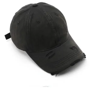 Close-up of distressed black cotton baseball cap with vintage frayed holes and worn texture