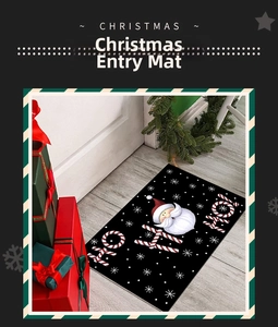Close-up of black Christmas door mat with Santa Claus and HO HO HO text on wood floor
