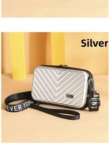 Detailed view of silver hard shell mini suitcase bag with Forever Young strap