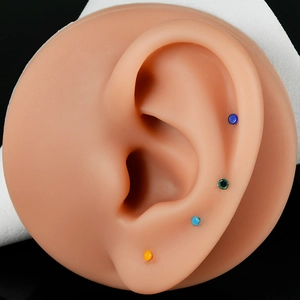 Set of four colorful round glass nose studs and ear cartilage earrings on a silicone ear model