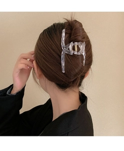 Detailed back view of a woman wearing a large transparent shark hair claw clip in a bun
