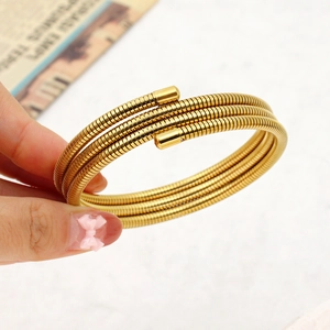 Detail of three-layer gold spiral spring bracelet showing polished finish and flexible steel