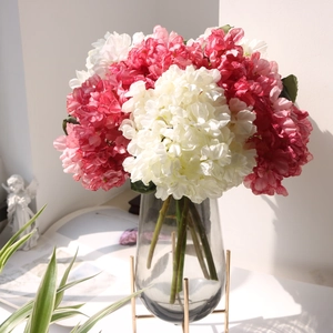 Detail of red and white artificial hydrangeas in a glass vase with metal stand
