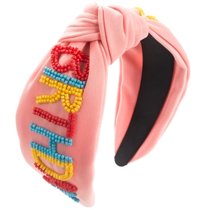 Détail d'un serre-tête rose noué orné de perles colorées formant le mot BRIGHT sur tissu