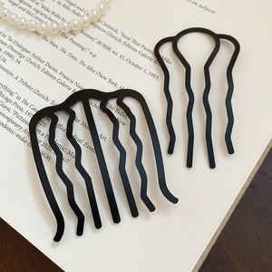 Détail de deux peignes à cheveux noirs ondulés sur un livre pour chignons