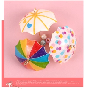 Close-up of mini resin umbrella pendants with rainbow and polka dot patterns for DIY crafts