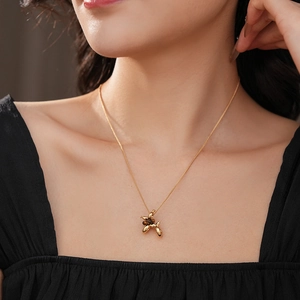 Detail of gold-plated balloon dog pendant necklace worn by a model in soft lighting