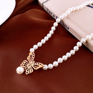 Choker élégant en perles avec pendentif papillon doré sur un tissu en velours marron