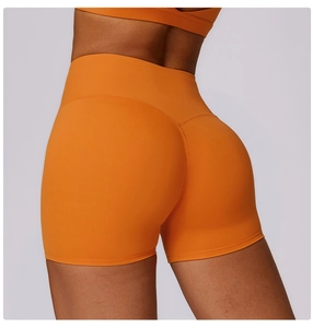 Detail view of high-waisted orange yoga shorts with slimming push-up back seams