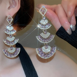 Close-up of tiered silver tassel earrings with purple crystals and fan-shaped drops