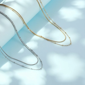 Double layered gold and silver snake bone necklaces with beads on blue background
