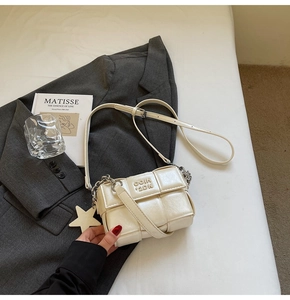 Détail d'un sac bandoulière blanc tressé avec breloque étoile et bandoulière en chaîne