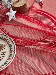 Detail of red lace Christmas table runner with festive knitted mesh pattern textures