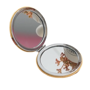 Portable double-sided round makeup mirror in gold frame showing interior folding design