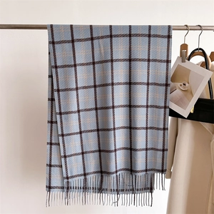 Detail of blue plaid cashmere-feel scarf with tassels hanging on a hanger
