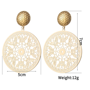 Detailed macro view of large hollow gold earrings with intricate floral and butterfly cutouts