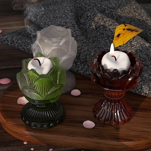 Detailed view of three lotus shaped glass candle holders in green and brown on a wood tray