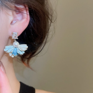 Detail of elegant fan-shaped pearl earring with blue gradient petals and zircon on model