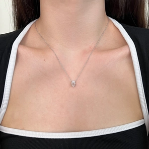 Detail showing an oval transparent gemstone pendant on a silver necklace worn by a model