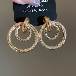 Détail de boucles d'oreilles double cercle dorées avec texture mate martelée fine