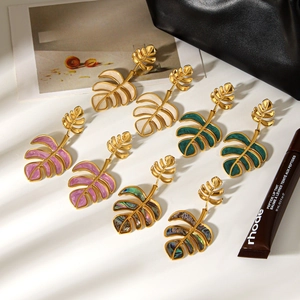 Golden monstera leaf drop earrings in cream, purple, dark green, and rainbow shell finish
