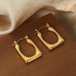 Gold geometric rectangle hoop earrings with radial texture on elegant wood and silk