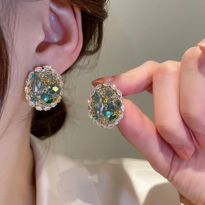 Close-up of vintage gold hoop earring with grey-green crystal and colorful beads