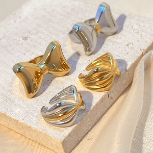Two-tone stainless steel rings featuring bow designs and wavy textures on stone surface