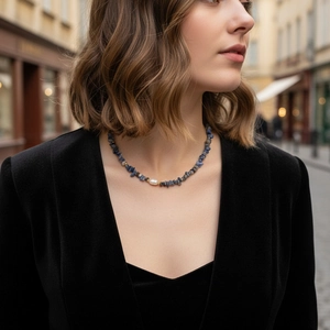 Detailed close-up of blue gemstone gravel and pearl necklace on a model's neck