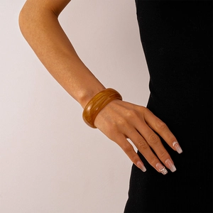 Detailaufnahme des bernsteinfarbenen Acryl-Armreifs mit sandiger, transparenter Textur