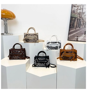 Detail of leopard print patchwork handbags displayed on white geometric stands in five colors