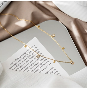 Detail of gold titanium steel necklace with rectangular zircons on soft silk fabric