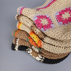 Detail of diverse handmade crochet patterns and floral color combinations on straw hats