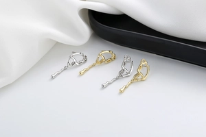 Detailed macro view of asymmetric 18K gold and silver streamlined minimalist earrings