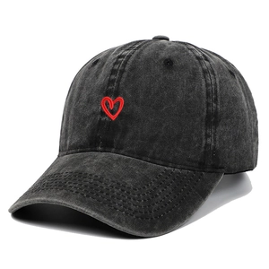 Dettaglio di un cappello da baseball in denim lavato grigio scuro con piccolo cuore ricamato.